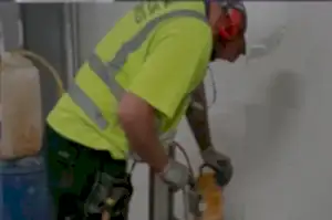 Worker in safety gear operating a concrete drilling machine, highlighting National Drilling Services' expertise in concrete drilling solutions.