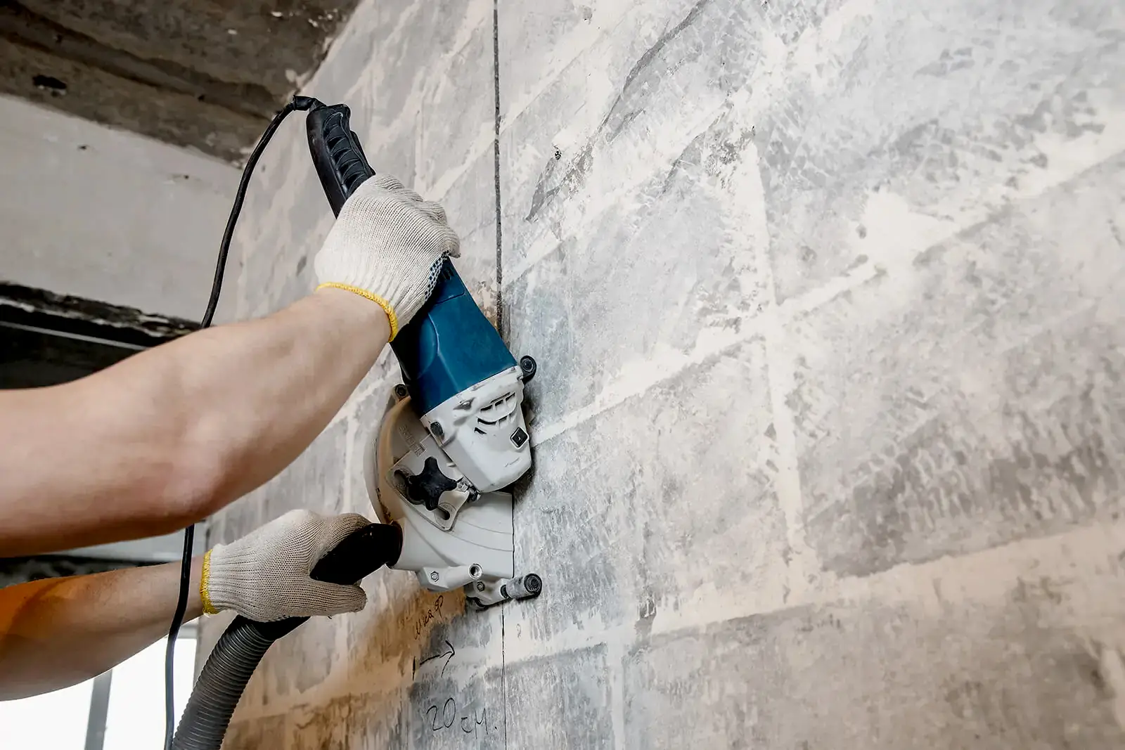 Person using a wall saw for concrete chasing, demonstrating drilling services in construction.