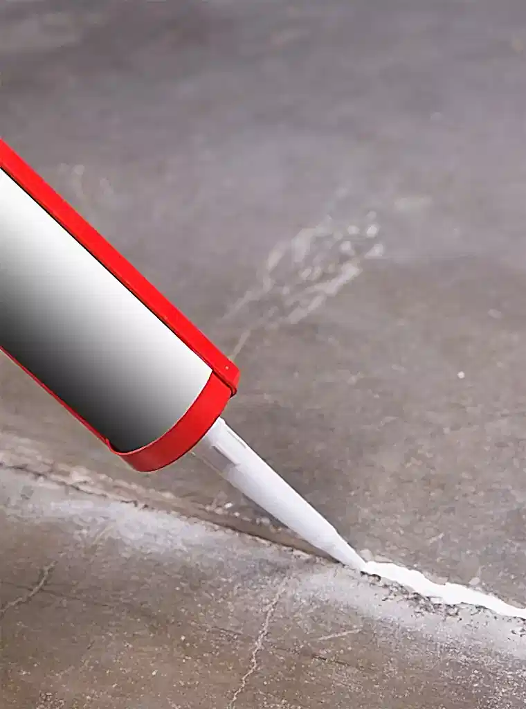 Concrete joint sealant application with caulking gun on industrial floor crack.