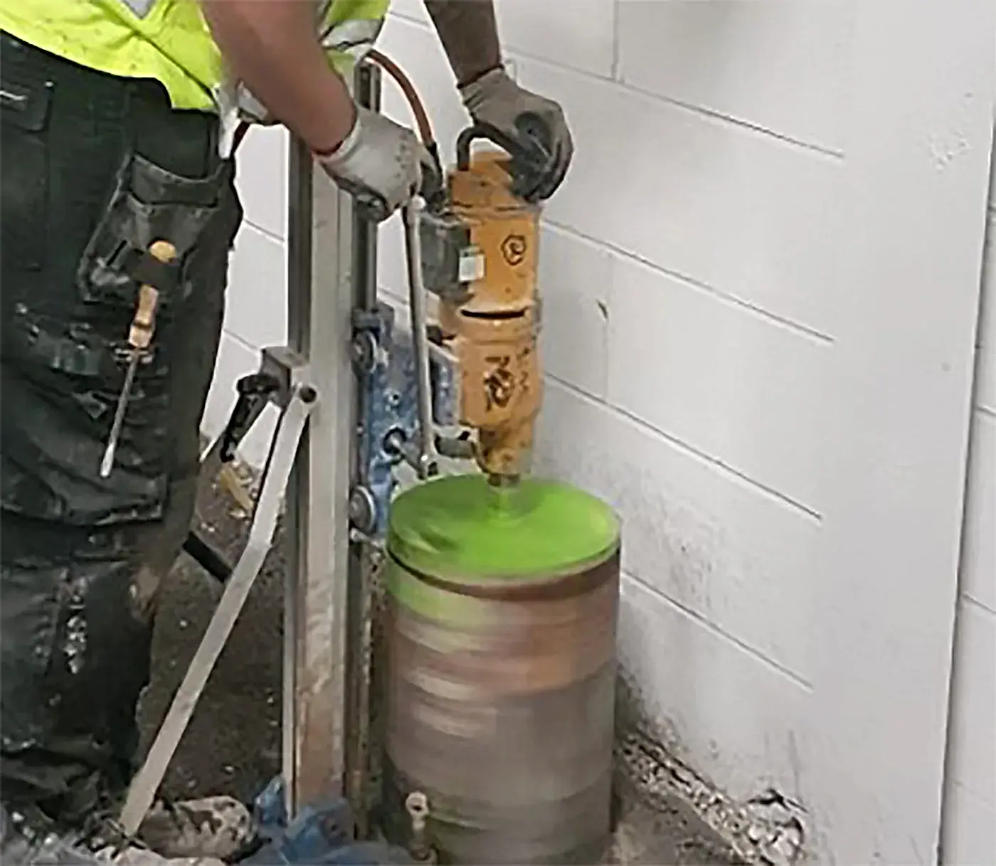 Worker operating a diamond core drilling machine on a concrete surface, demonstrating National Drilling Services' expertise in diamond drilling services.
