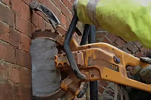 Ring sawing tool being used on a brick wall, showcasing concrete cutting services by National Drilling Services.