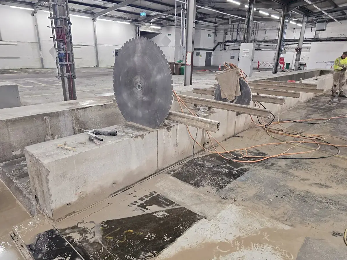 Track saw equipment on concrete blocks in an industrial setting, highlighting precision cutting tools and construction debris, relevant to concrete floor sawing services offered by National Drilling Services.