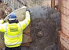 Worker operating track wall sawing equipment, showcasing precision cutting in masonry, with visible branding for National Drilling Services.