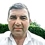 Paul Cassidy, representative of National Drilling Services Ltd, in a white shirt against a green hedge backdrop, emphasizing expertise in drilling and demolition services.