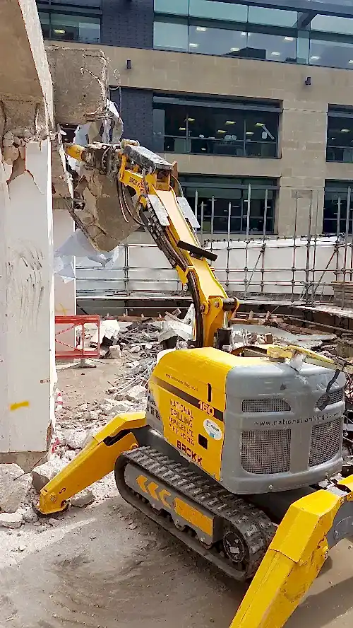 Robotic demolition machine from National Drilling Services breaking down a wall in a construction site, showcasing advanced demolition technology for efficient site clearance.