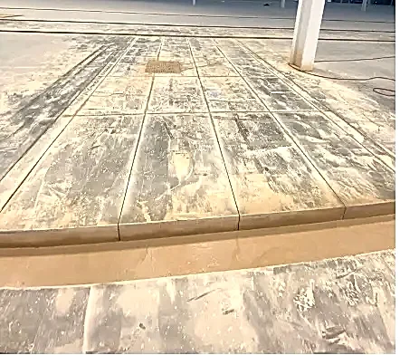 Concrete floor with cut sections and dust, illustrating National Drilling Services' concrete cutting project for a construction site.
