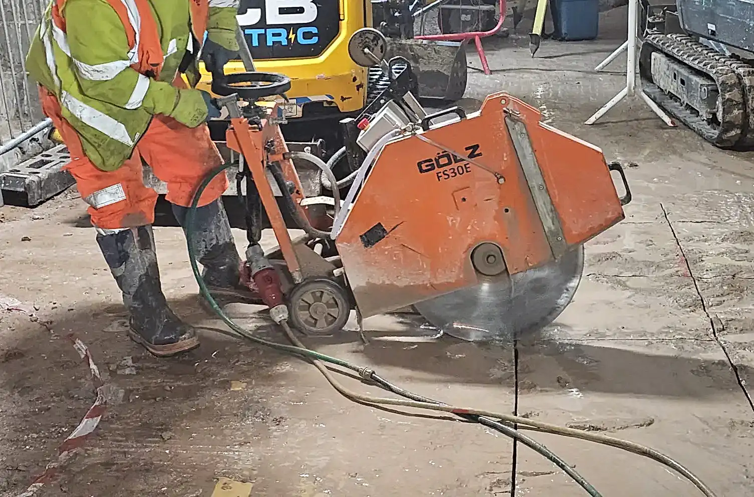 Electric floor saw in use by contractor, cutting concrete surface with precision, showcasing National Drilling Services' expertise in construction.