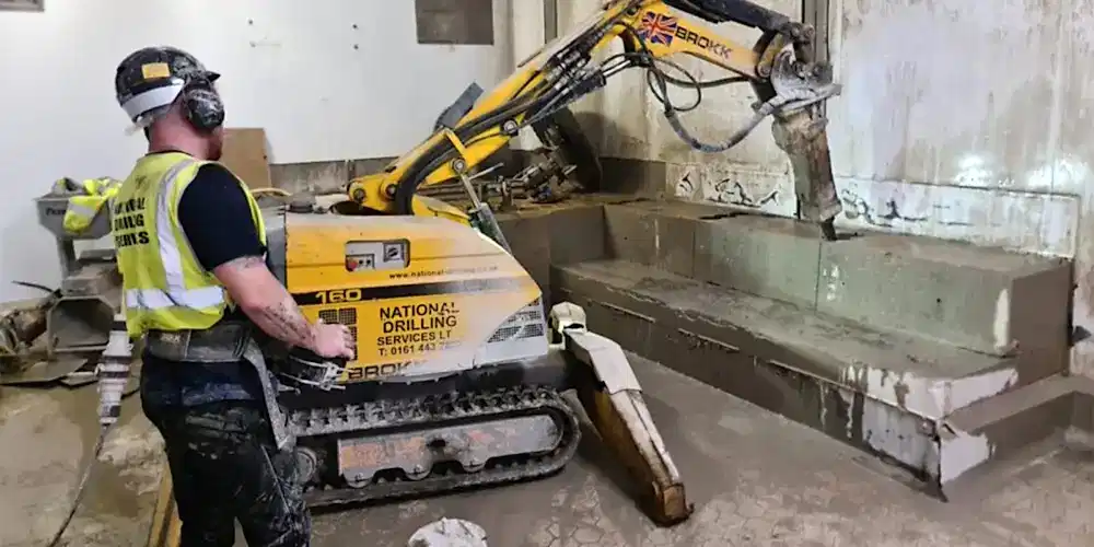 Operator using Brokk demolition robot for precision drilling at construction site, showcasing National Drilling Services expertise in diamond core drilling.