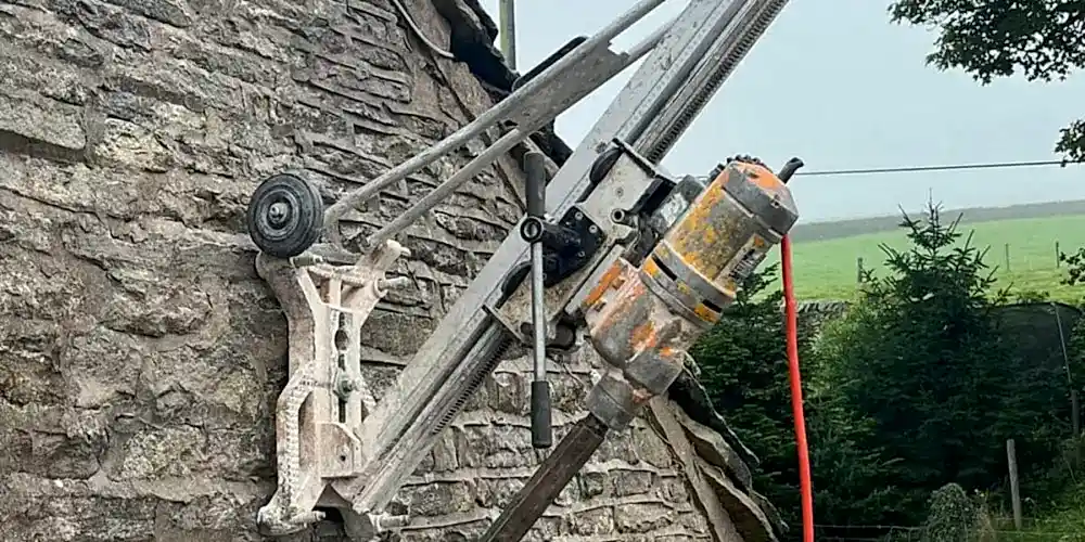 Diamond core drilling equipment mounted on a stone wall, showcasing precision drilling capabilities for construction and engineering needs.